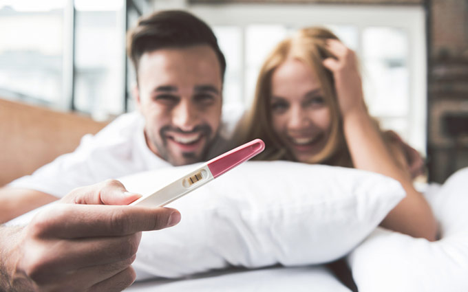 Happy couple holding a positive pregnancy test