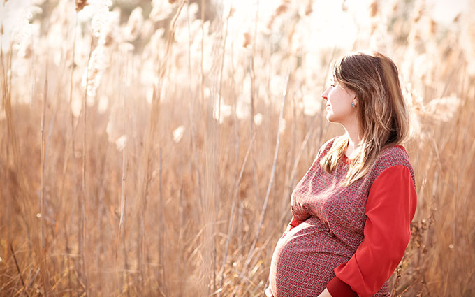 Woman smiling while holding her pregnant belly