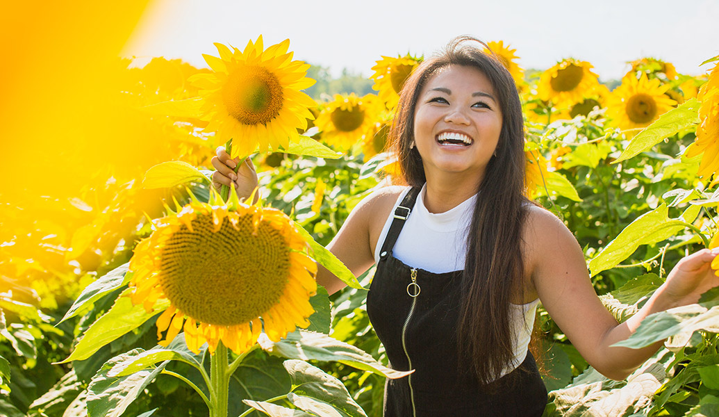 Happy Asian woman in a field of sunflowers