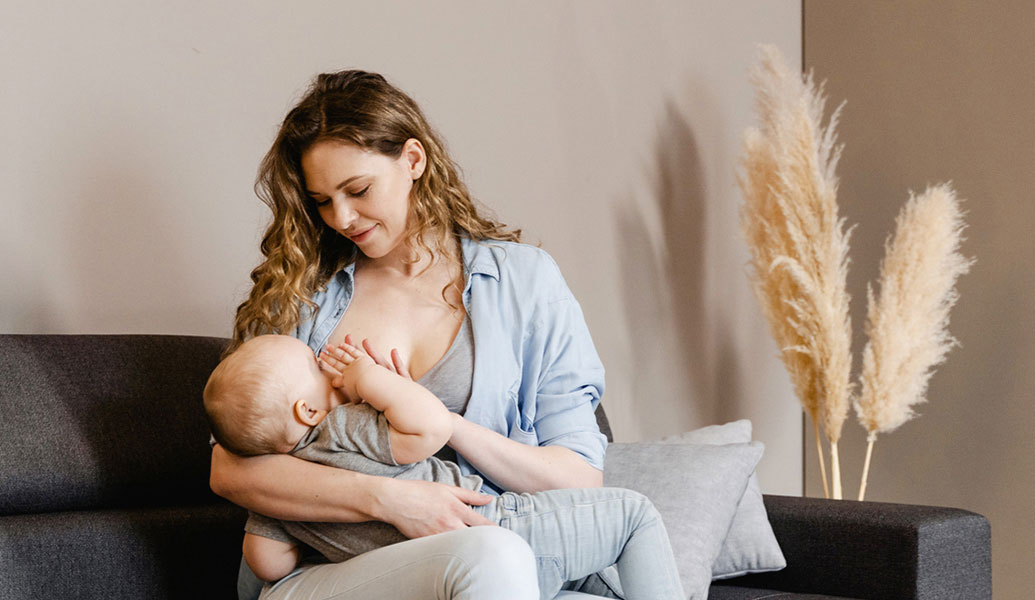 Mum breastfeeding her baby sitting on a couch