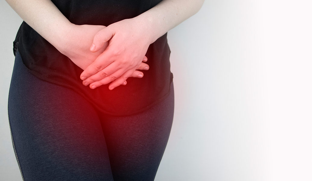 Woman in black workout clothes clutching her abdomen