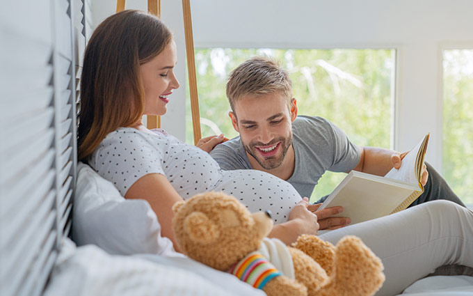 man reading to pregnant womans belly