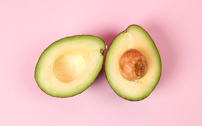 Avocado halves on a pink background