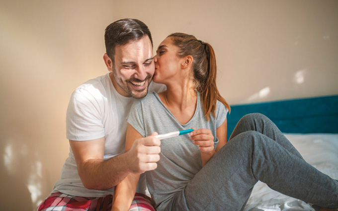 Happy couple holding a positive pregnancy test