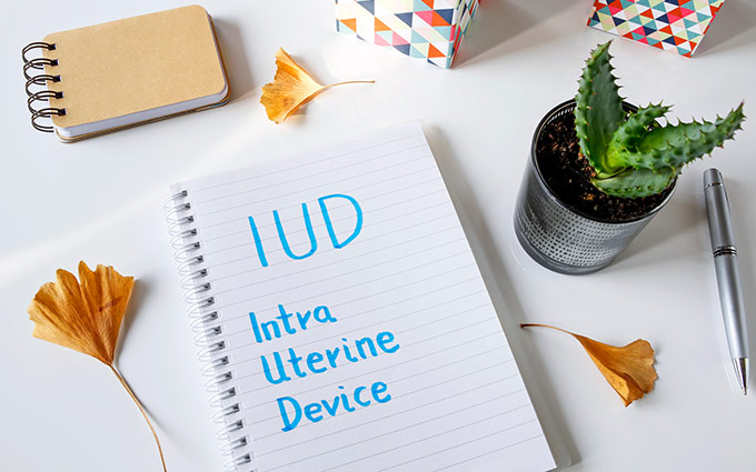 IUD Intra Uterine Device written in notebook on white table