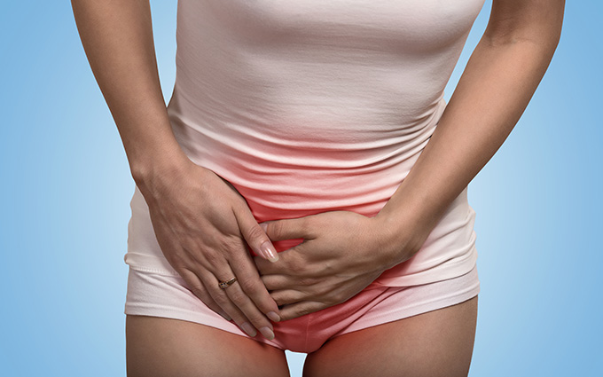 Close up cropped image of a woman with hands holding her crotch lower abdomen isolated on blue background