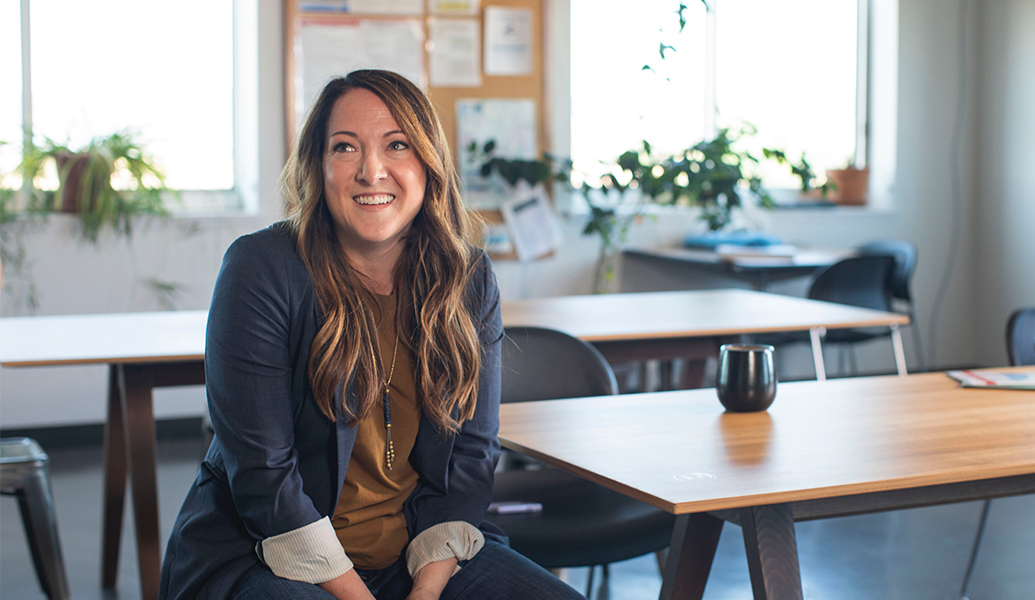 woman sitting at a table looking off to the left with a smile