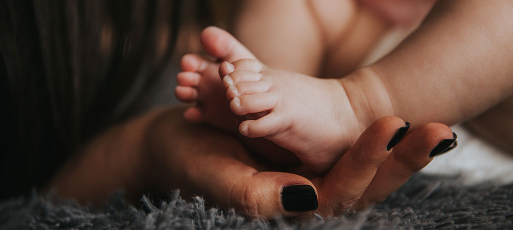 Closeup of baby feet resting on a parent's hand